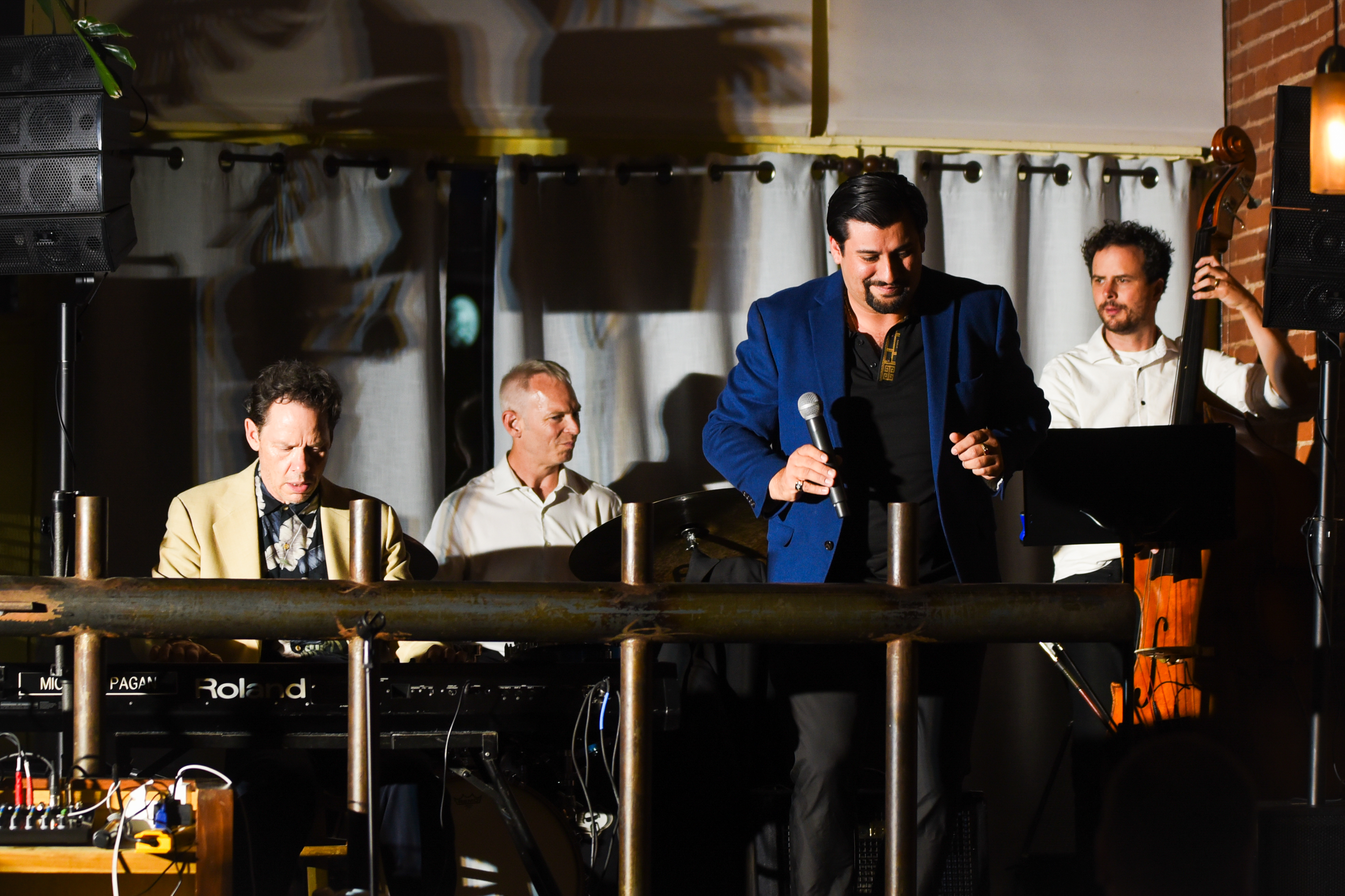 Full band on stage — keyboards, drums, vocals, and upright bass